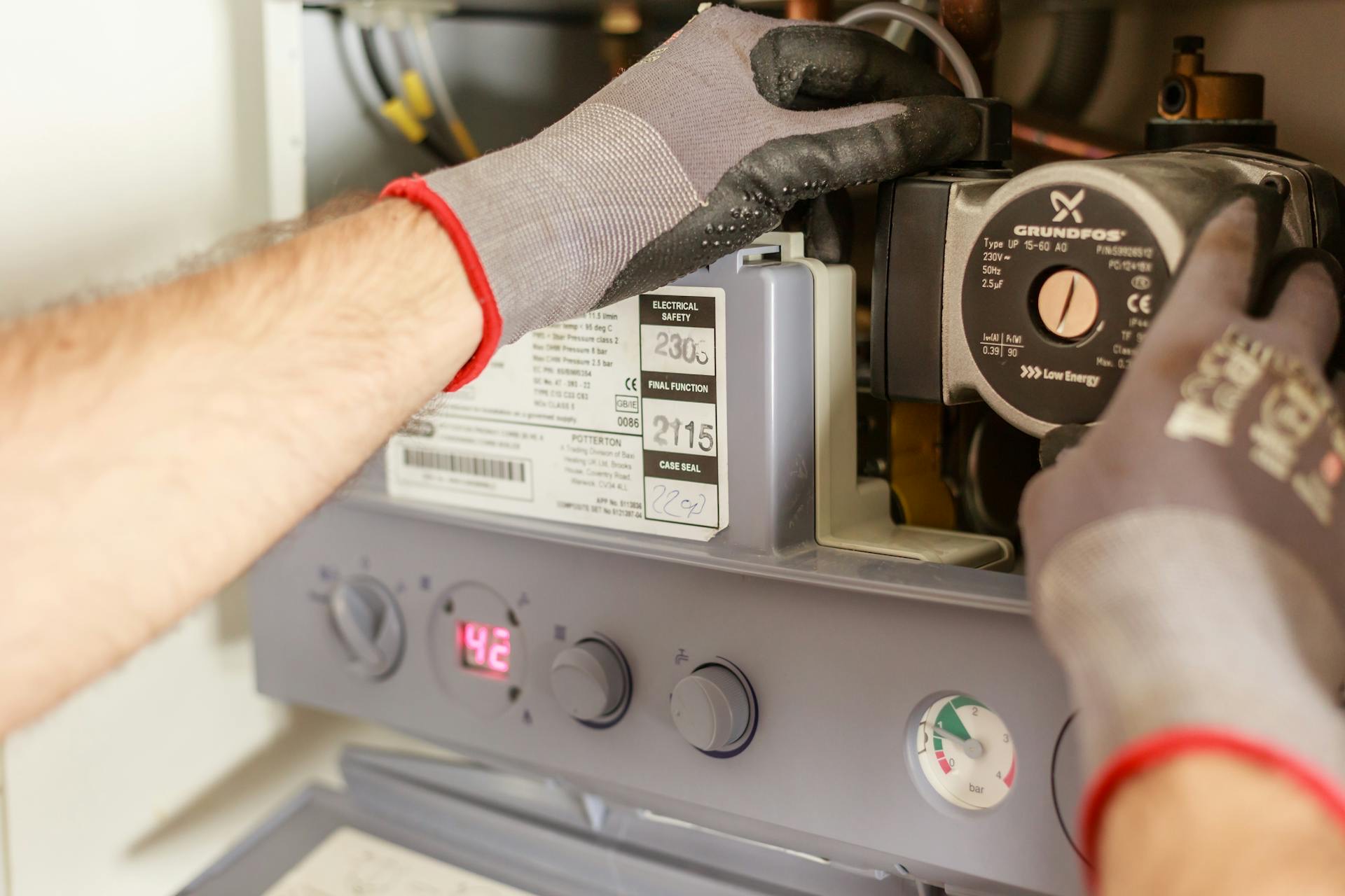 Mains manipulant les composants internes d’une chaudière.